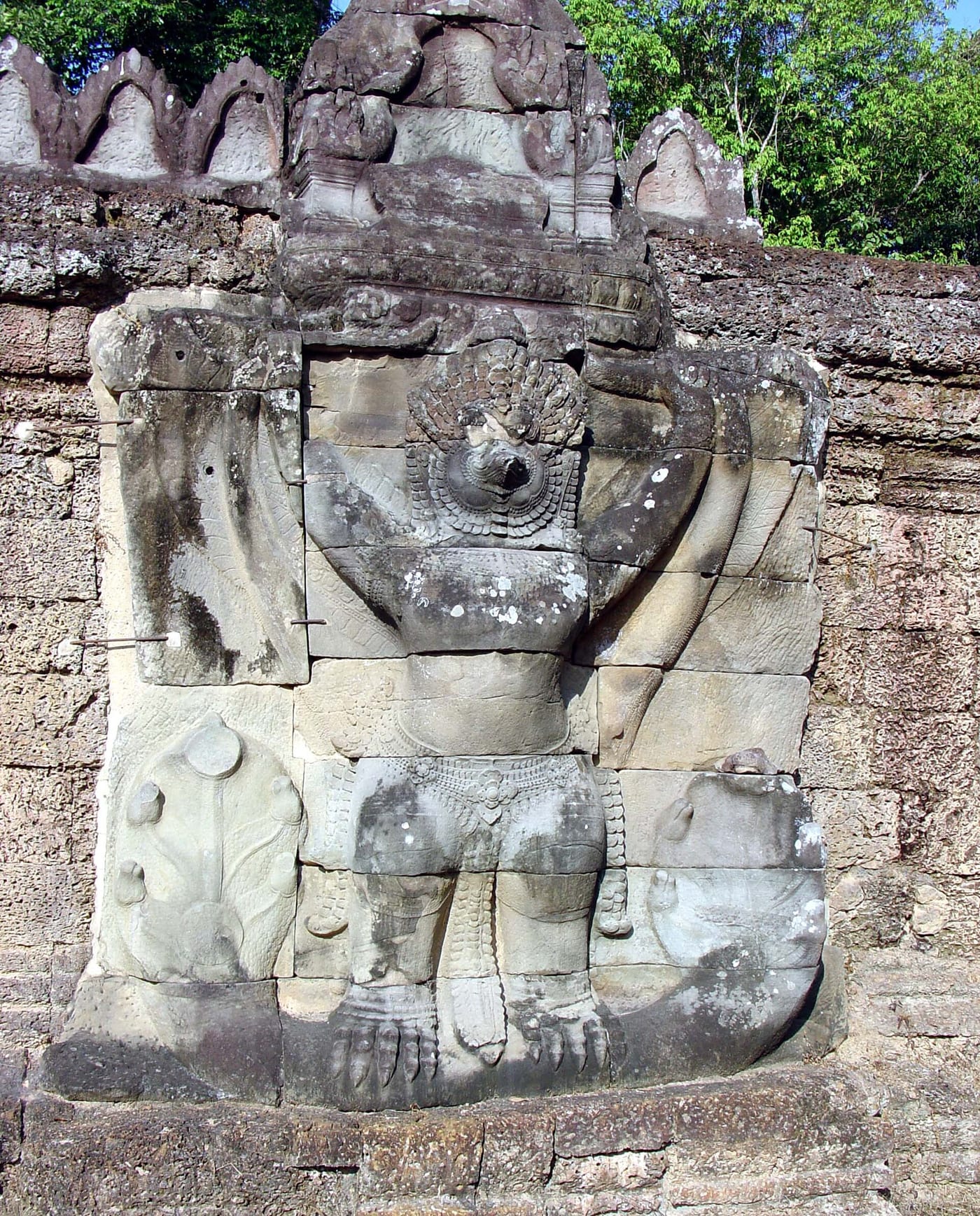 Stone relief at Angkor Wat, Cambodia, 12th century CE, showing Garuda — the divine eagle-mount of Vishnu — in his characteristic wings-spread posture with naga serpents in hand.