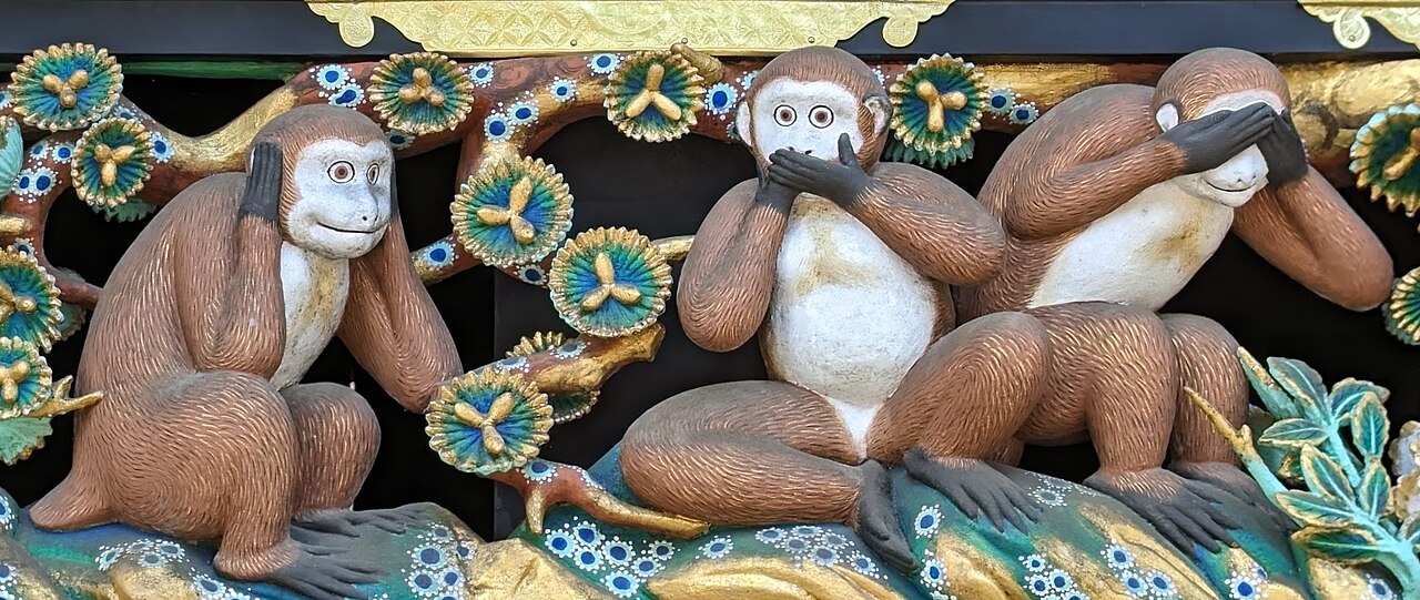 Carved and painted wooden panel of three monkeys, the first covering its eyes, the second its ears, the third its mouth, against a background of gilded foliage.