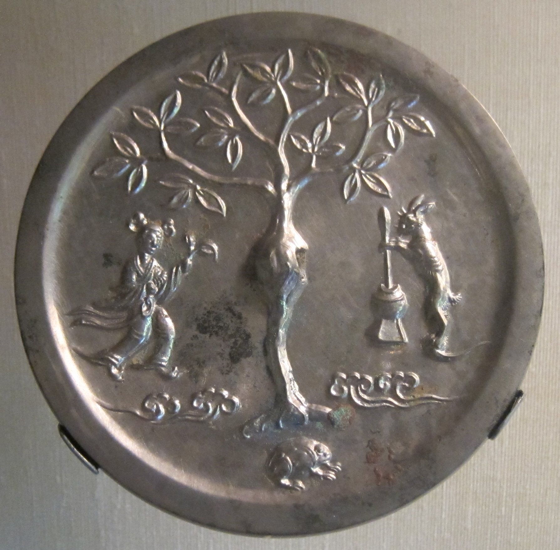 Tang dynasty Chinese bronze mirror back showing the moon goddess Chang'e with the moon-rabbit (yutu) pounding the elixir of immortality beneath the cassia tree.