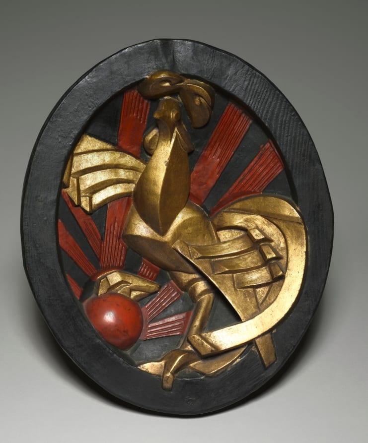 Modernist painted bronze relief of a rooster reduced to angular gilded planes against red and black rays, set in a dark oval frame.