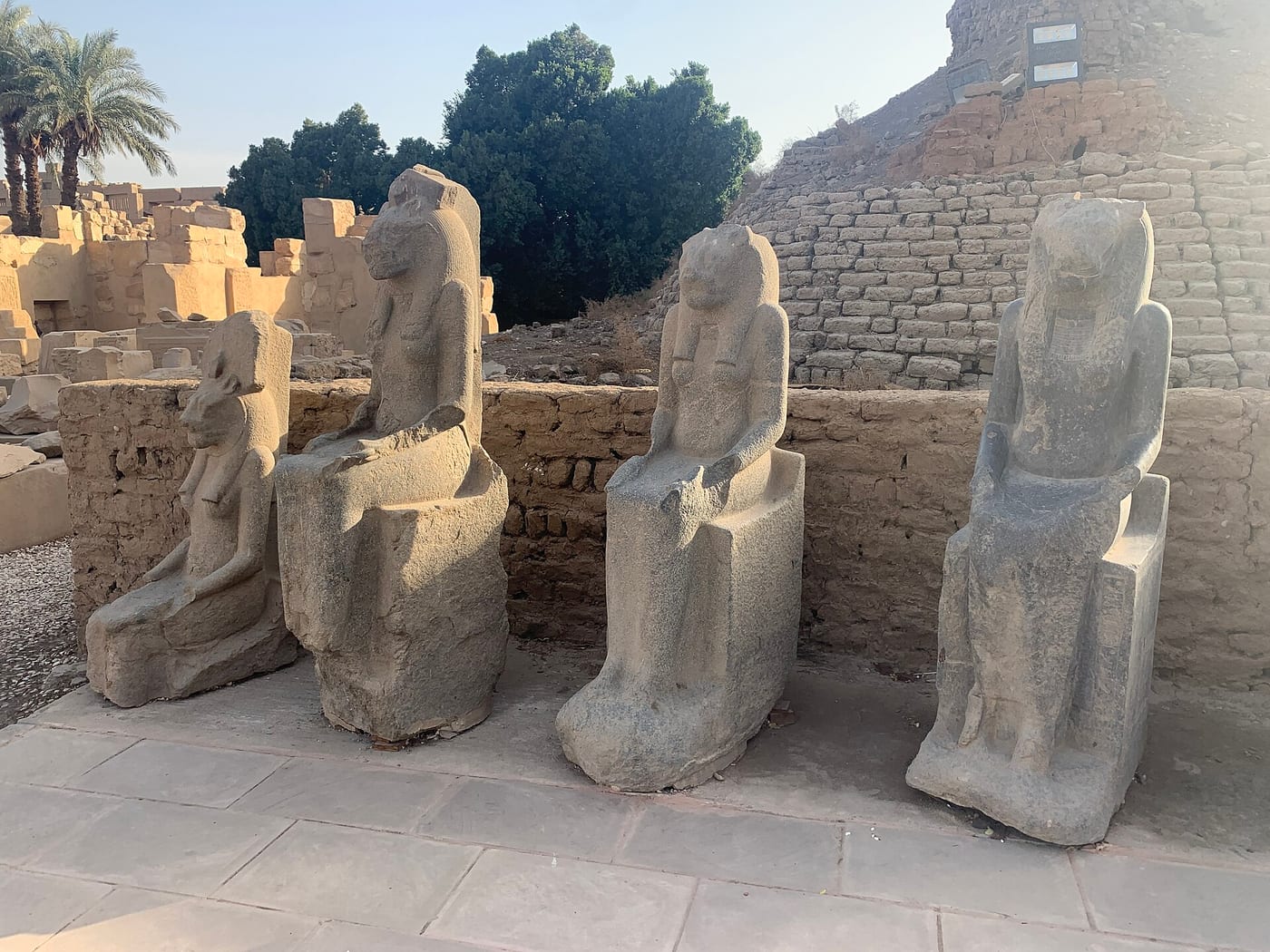 Row of black granodiorite Sekhmet statues lining the processional way at Karnak Temple, Luxor, Egypt, showing dozens of seated lioness-headed goddess figures, each wearing a sun disk, from Amenhotep III's commission, c. 1390–1353 BCE.